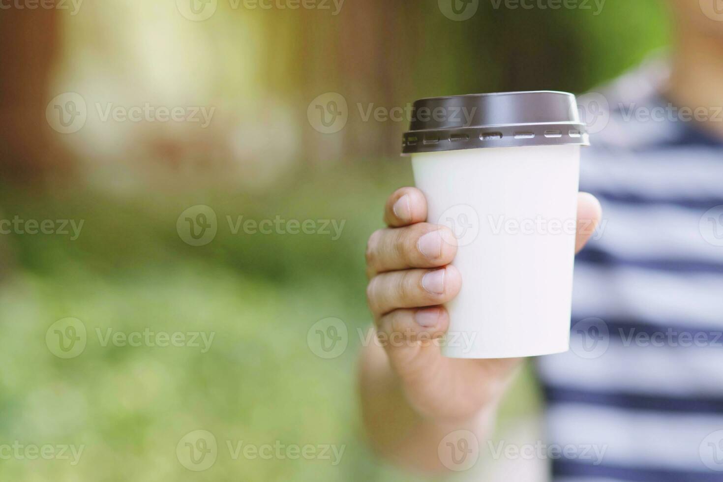 hand holding paper cup of take away drinking coffee  on natural morning sunlight. space place for your logo. Leave space for writing text. photo