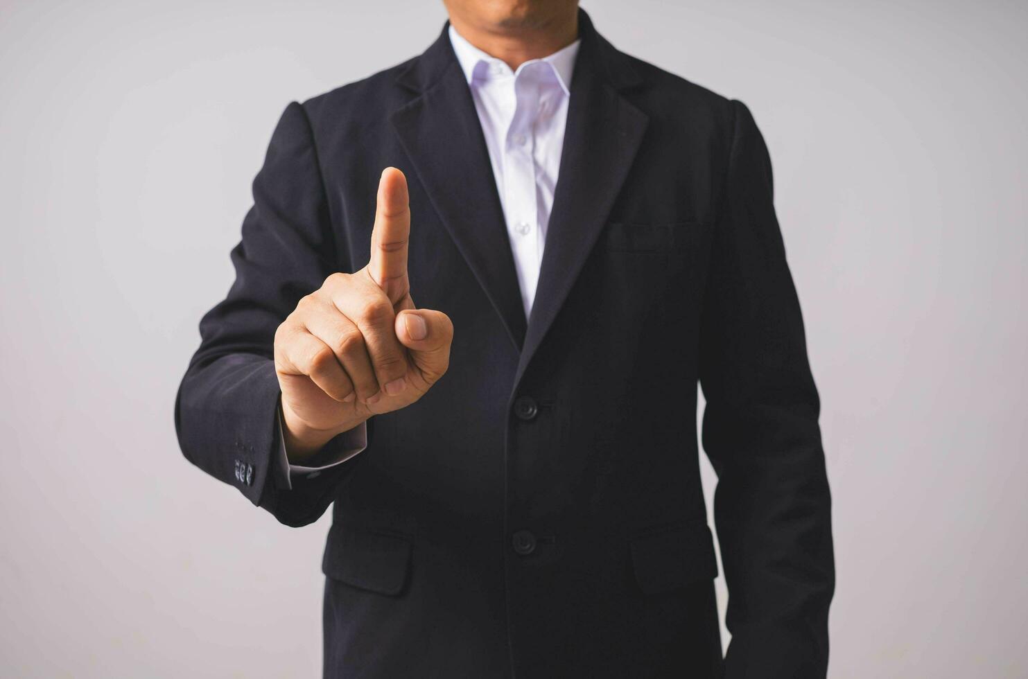 A businessman in a black suit stands and raises his hands. photo