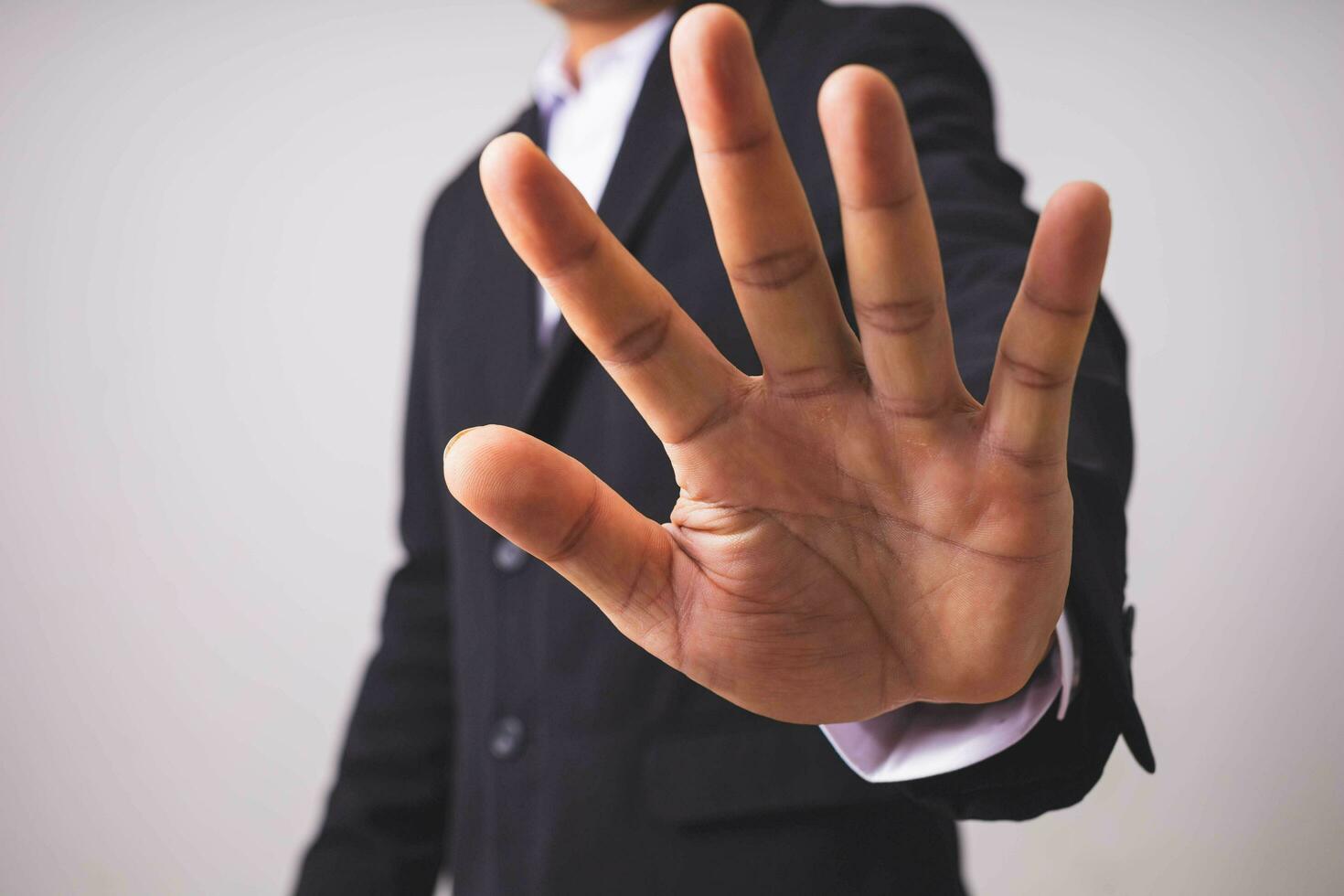 A businessman in a black suit stands and raises his hands. photo