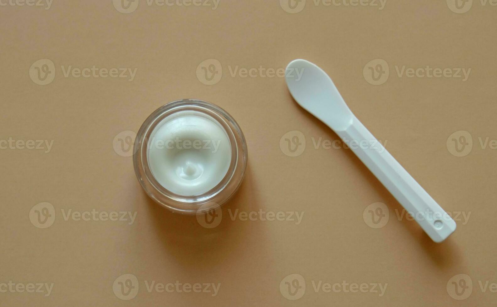 Plastic jar of beauty cream or mask for face care with spatula on pastel background, top view. Concept of skincare cosmetic, cosmetic spa medical skin care. Natural cosmetics concept. photo