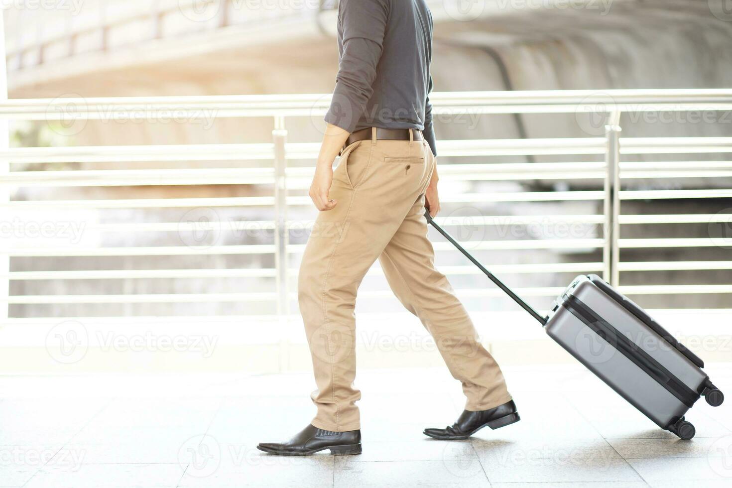 businessman walking outside public transport building with luggage in rush hour. Business traveler pulling suitcase in modern airport terminal. baggage business Trip. photo
