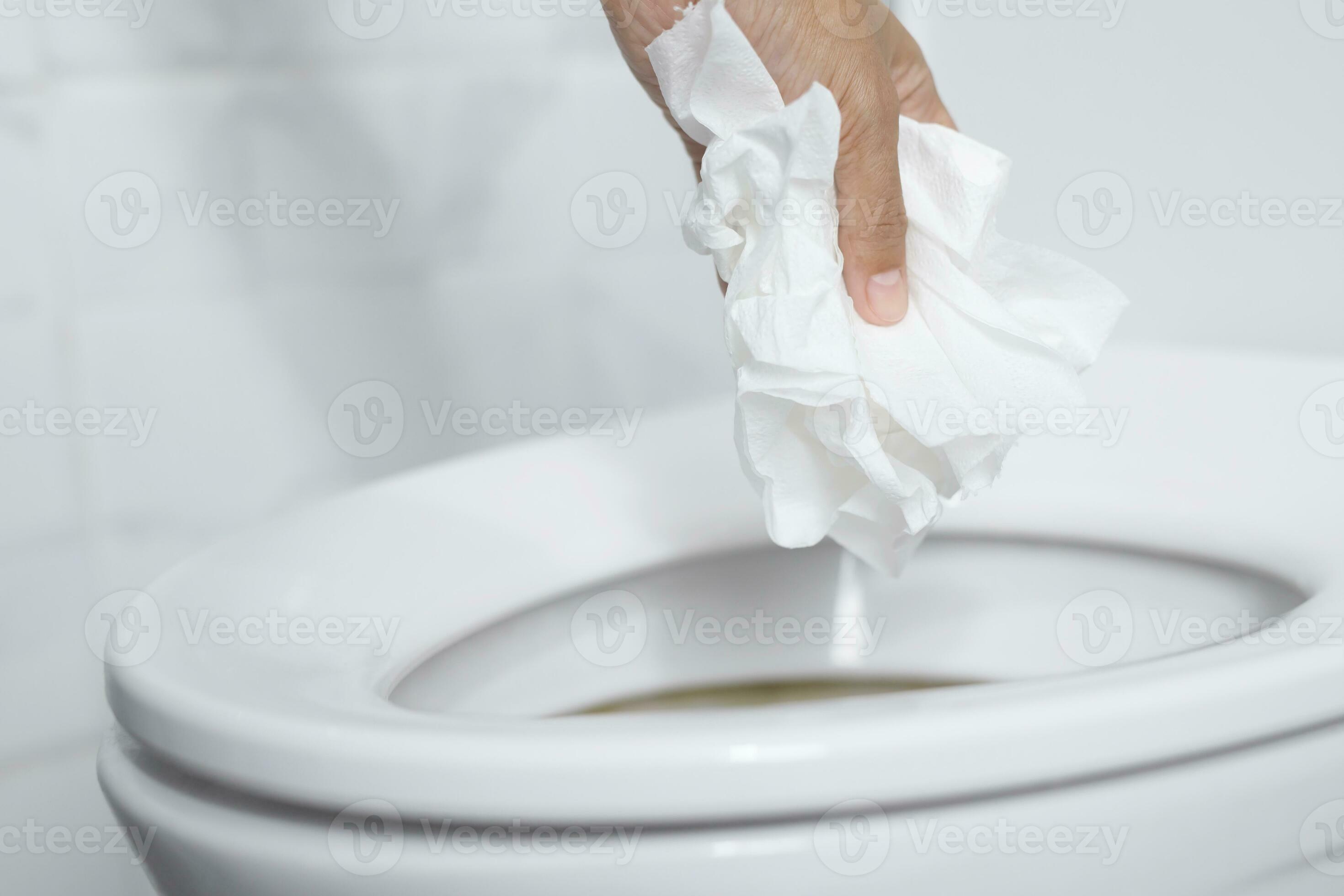 close up hand holding a tissue to be thrown into the toilet bowl. Can