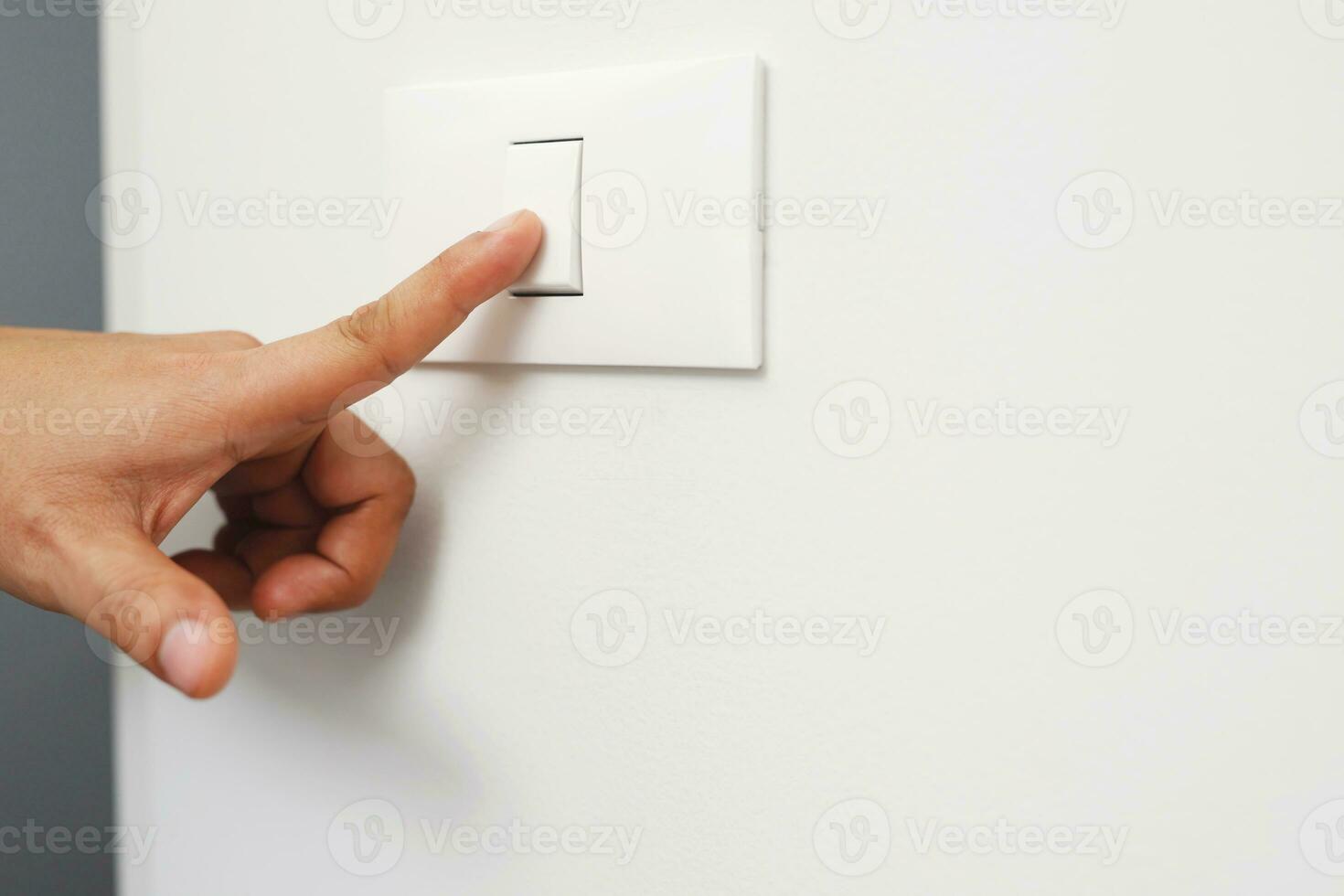 Turn off the light, close up finger man hand is closing the power switch with wall at home  to save energy. reduce global warming. photo