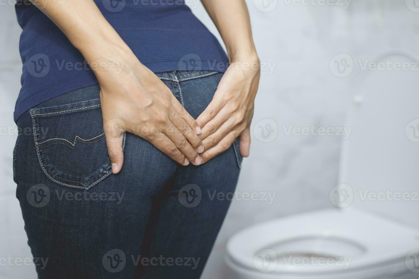 portrait of a woman suffers from diarrhea his stomach painful. ache and problem. hand hold tissue paper roll in front of toilet bowl. constipation in bathroom. Hygiene, health care concept. photo