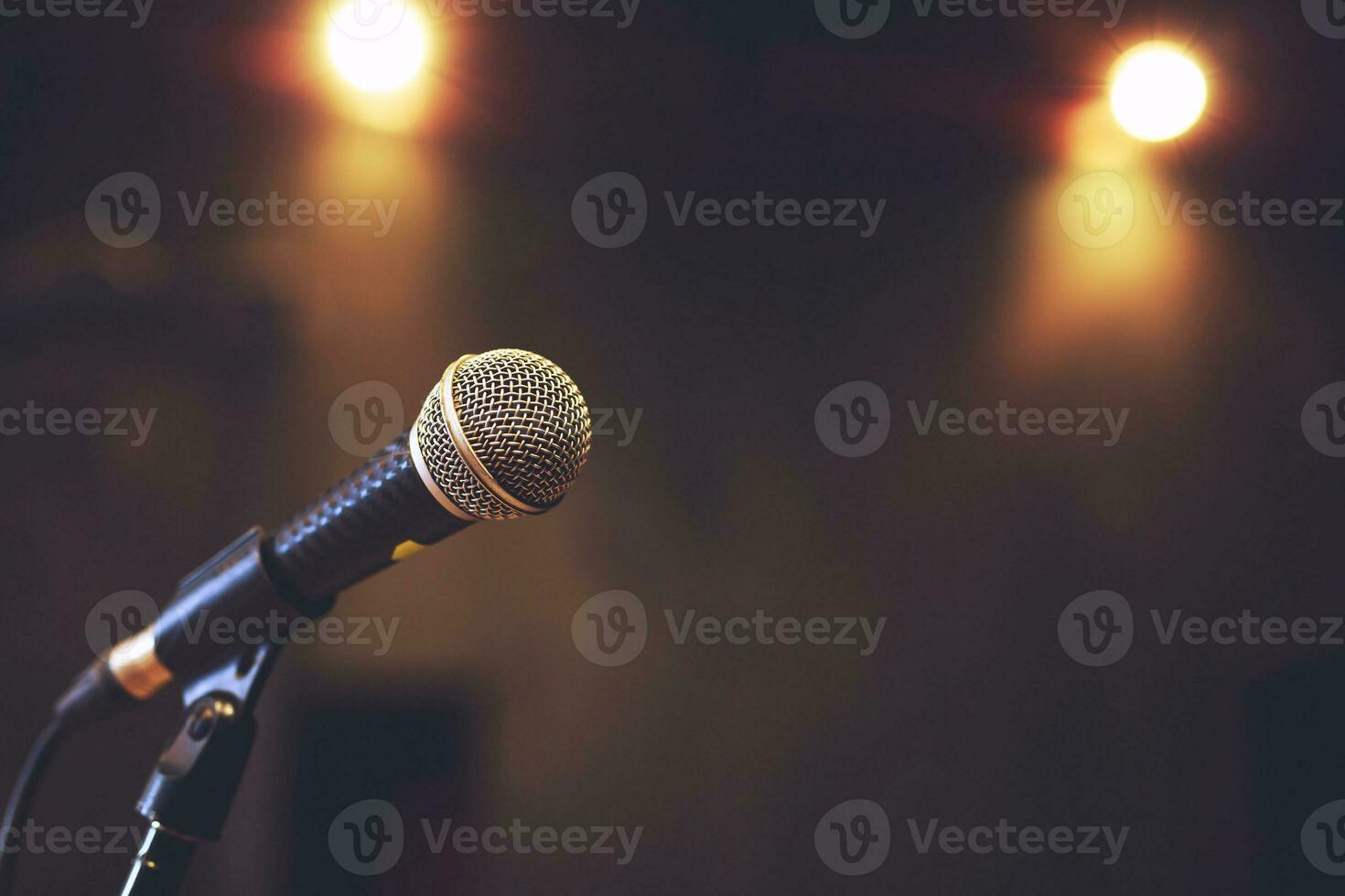 primer plano del micrófono en la iluminación del escenario en la sala de conciertos o sala de conferencias. copie la pancarta del espacio. enfoque suave. foto