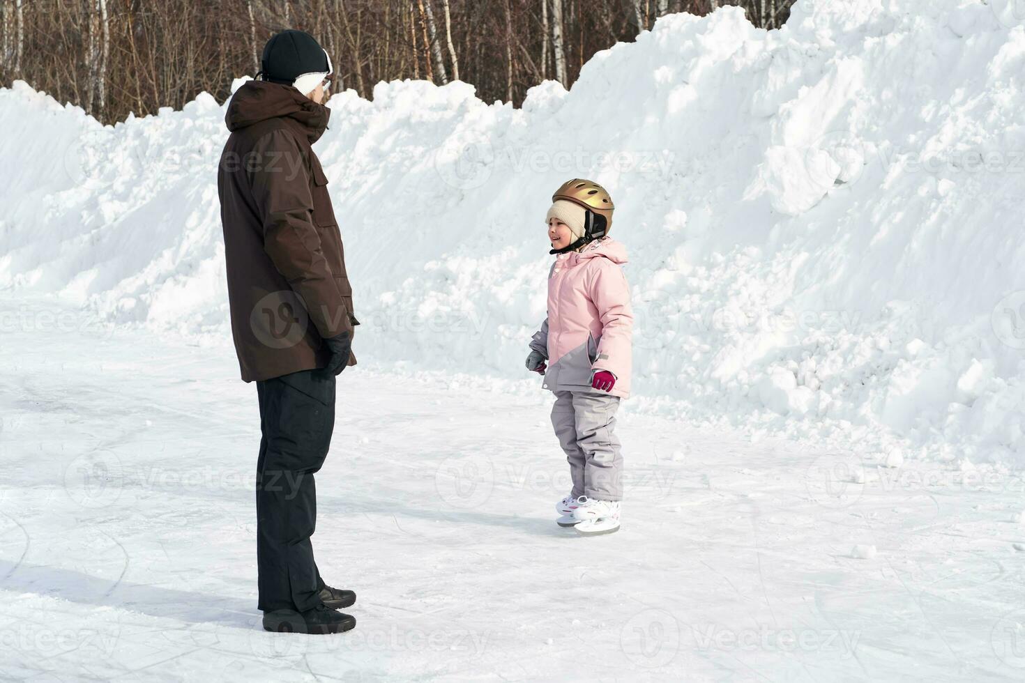 A girl in winter clothes learns to skate. photo