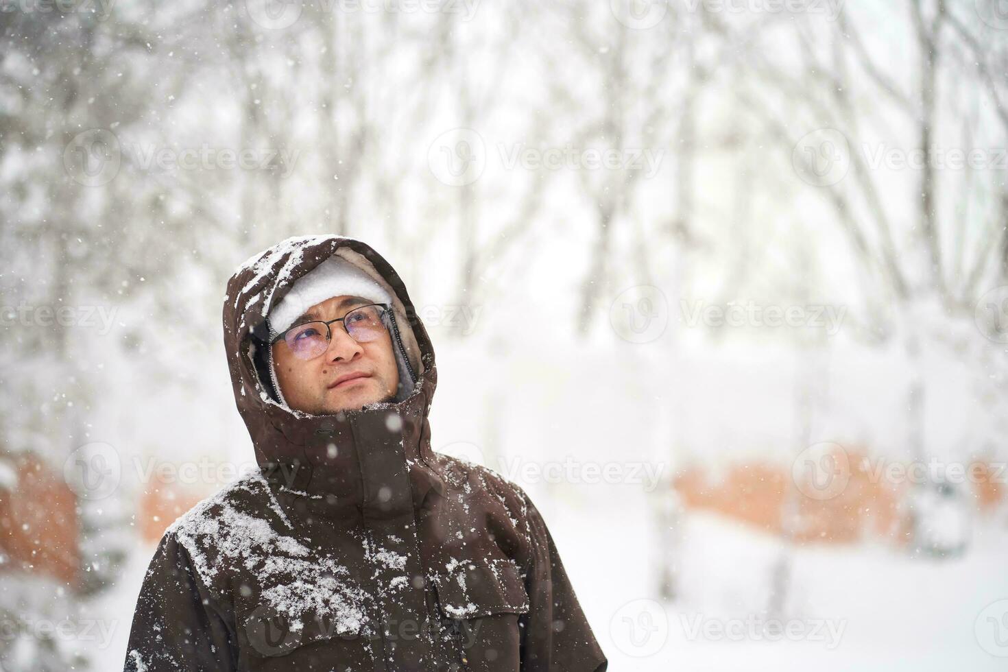 A man in winter clothes stands on the street. photo