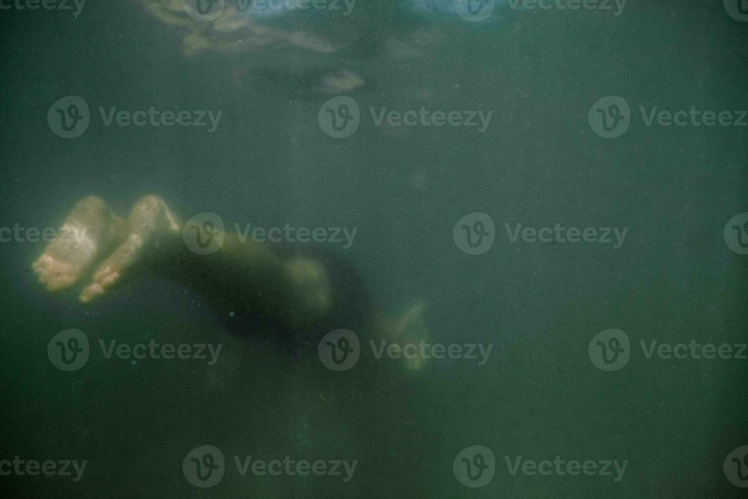 a person swimming underwater with their feet in the water photo