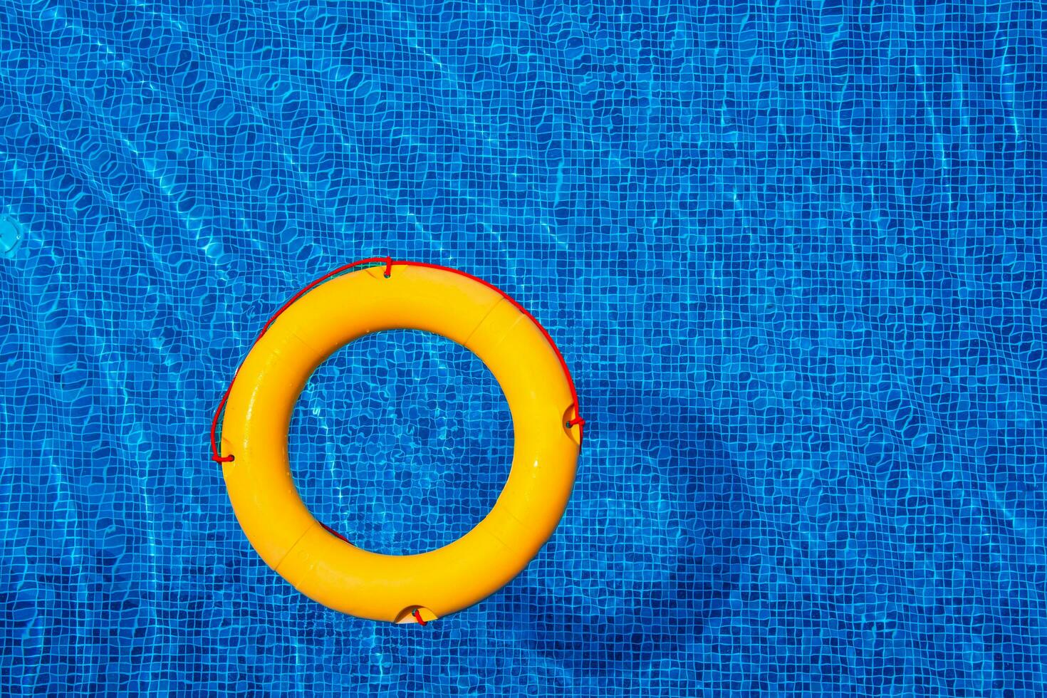 Top view of lifebuoy floating in blue swimming pool, soft focus. photo