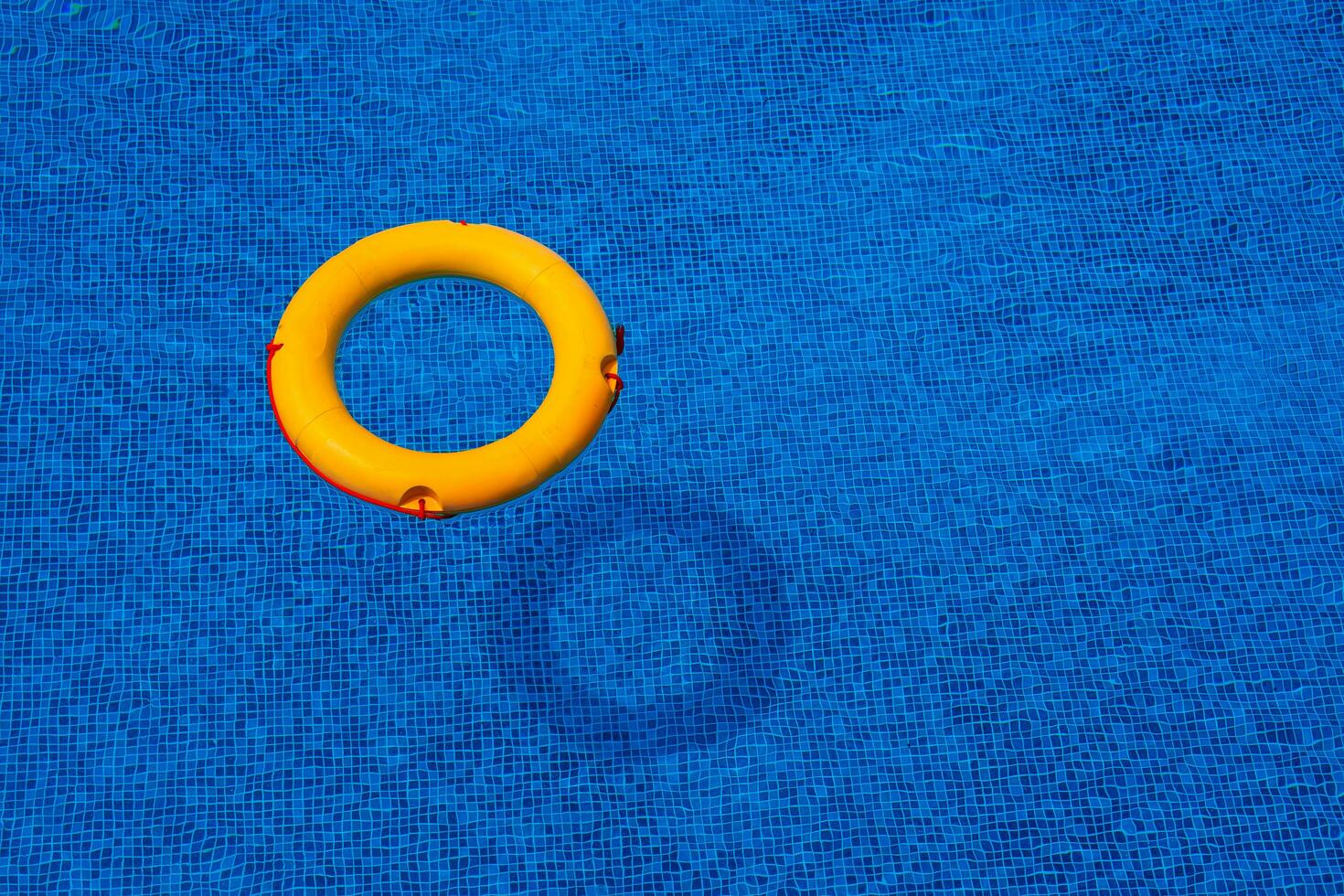 Top view of lifebuoy floating in blue swimming pool, soft focus. photo