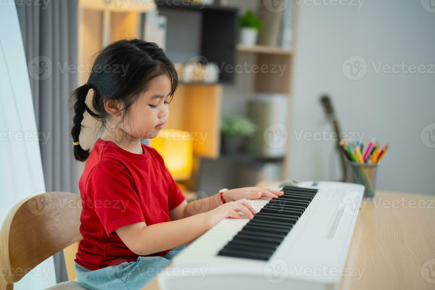 Happy little asian cute baby girl smile playing learning online piano music in living room at home. The idea of activities for child at home during quarantine. Music learning study. photo