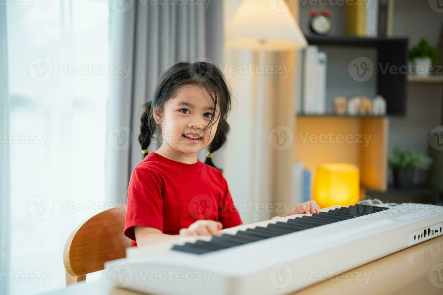 Happy little asian cute baby girl smile playing learning online piano music in living room at home. The idea of activities for child at home during quarantine. Music learning study. photo