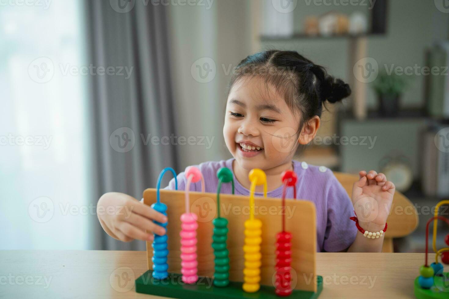 Young cute Asian baby girl is learning the abacus with colored beads to learn how to count on the table in the living room at home. Child baby girl development studying concept. photo