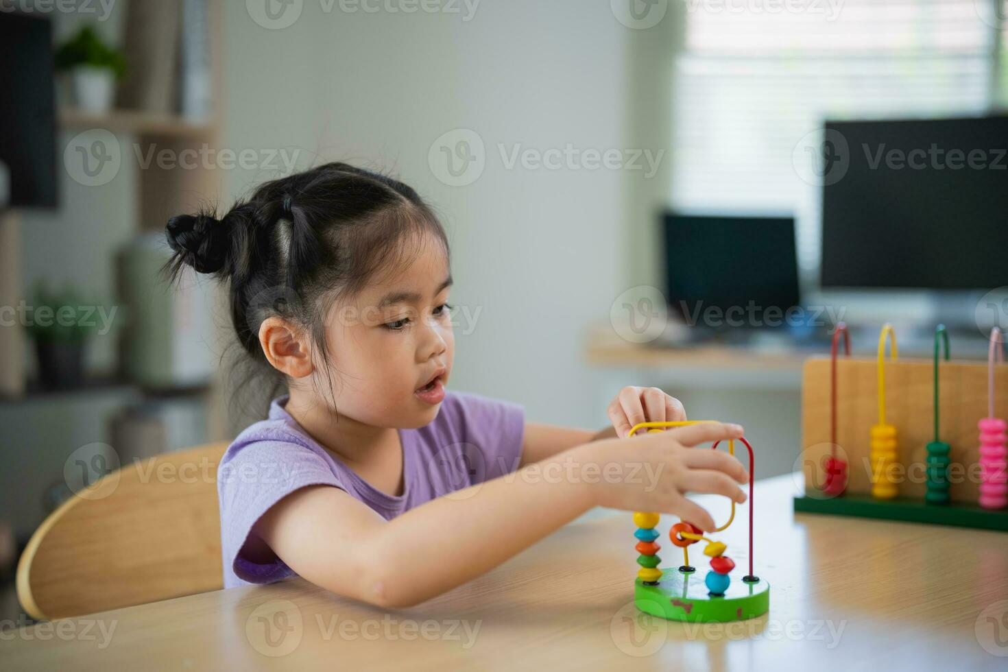 Young cute Asian baby girl is learning the abacus with colored beads to learn how to count on the table in the living room at home. Child baby girl development studying concept. photo