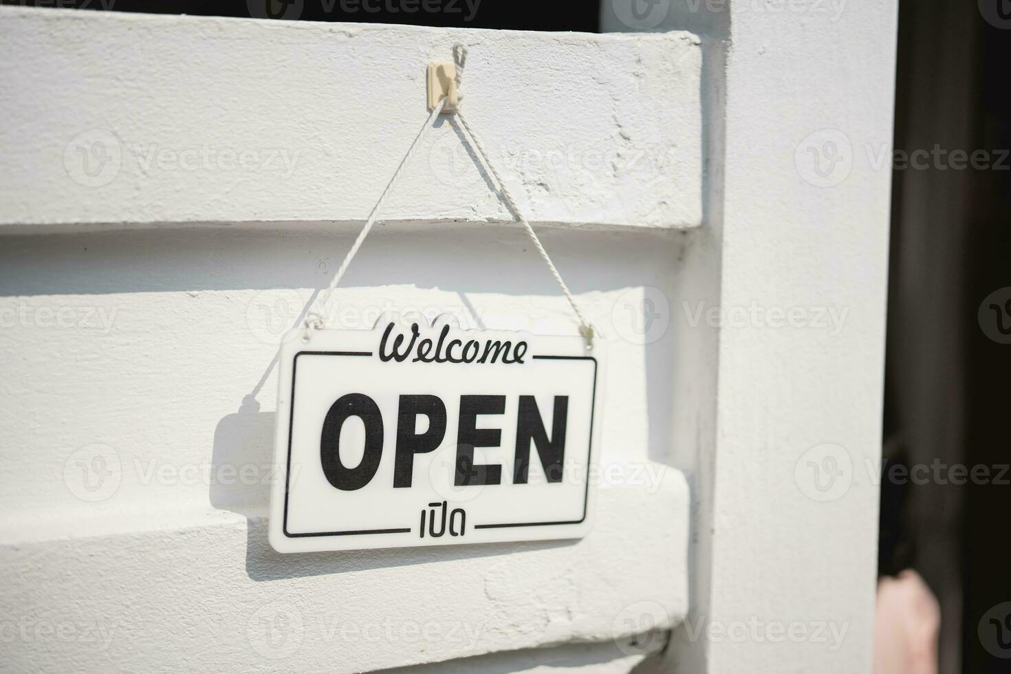 Open sign broad through the white wall background. OPEN sign board through the glass of store window. white text wooden board door vintage shop sign opened store. photo