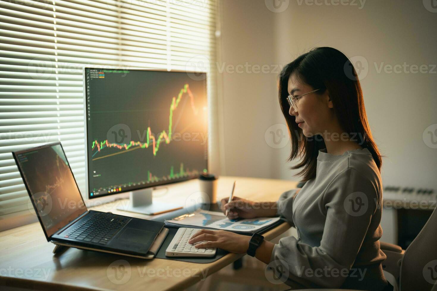 Asian Business Woman is checking Bitcoin or stock market price chart on the digital exchange on a laptop monitor computer, cryptocurrency future price action prediction. Trading Stock Bitcoin ETF. photo
