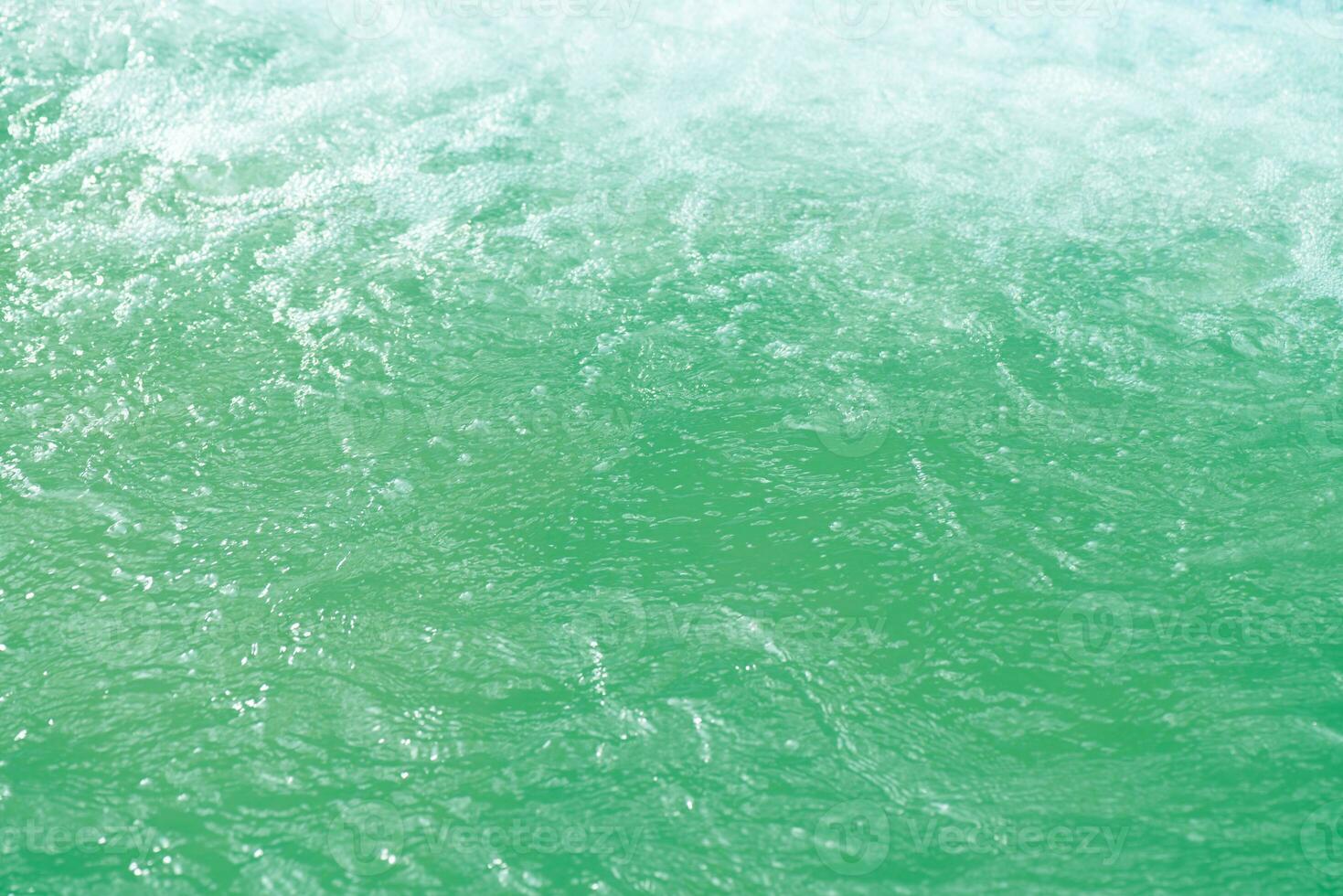 Defocus blurred transparent blue colored clear calm water surface texture with splashes and bubbles. Trendy abstract nature background. Water waves in sunlight with copy space. Blue watercolor shining photo