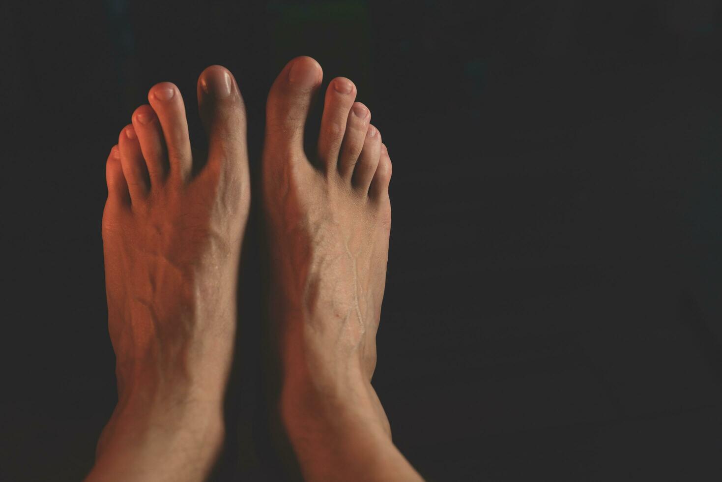 male feet in the dark. Close-up of man's bare feet photo