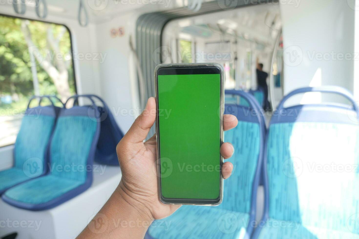 young man hand using smart phone with green screen inside of metro train photo