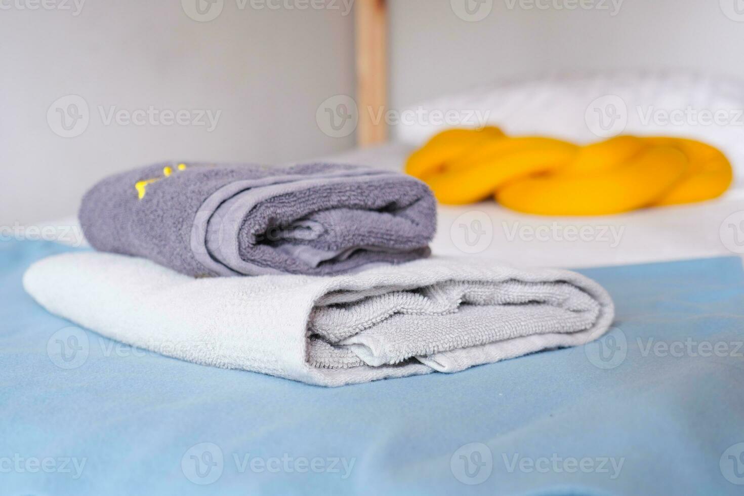 pile of gray and white color shower towel on bed photo