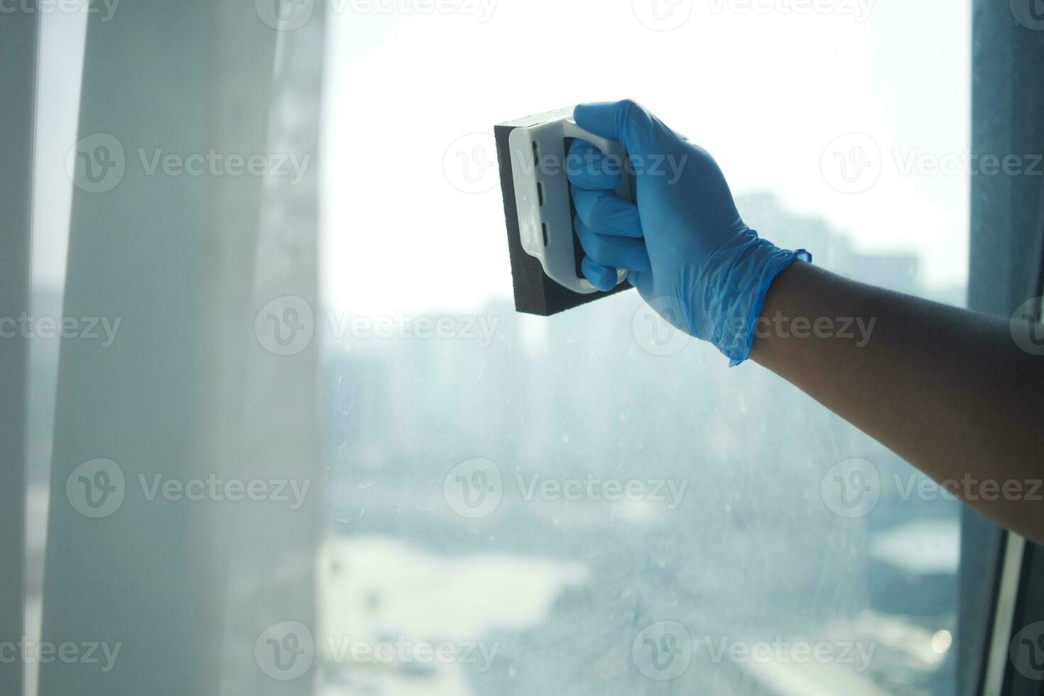 person hand in gloves cleaning window glass photo