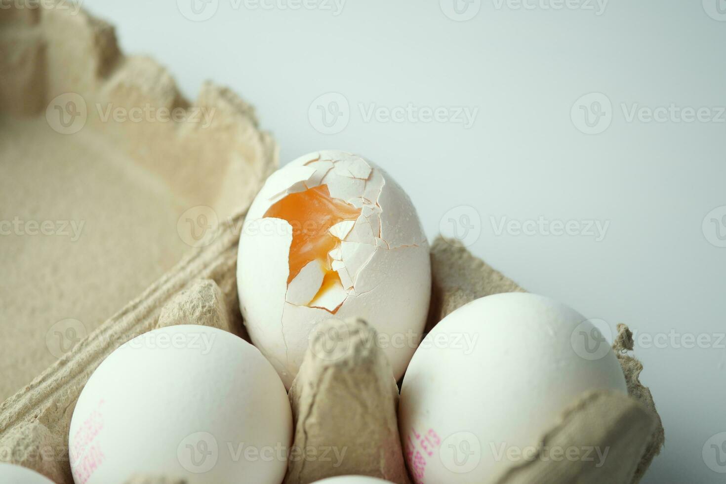 one broken egg with yellow yolk stored in carton container photo