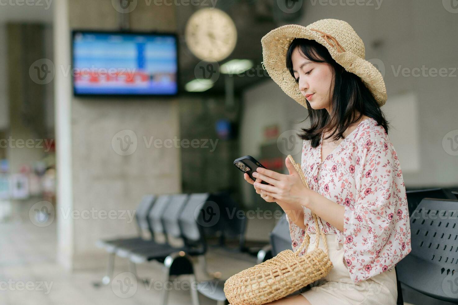 young asian woman traveler with weaving basket using a mobile phone and waiting for train in train station. Journey trip lifestyle, world travel explorer or Asia summer tourism concept. photo