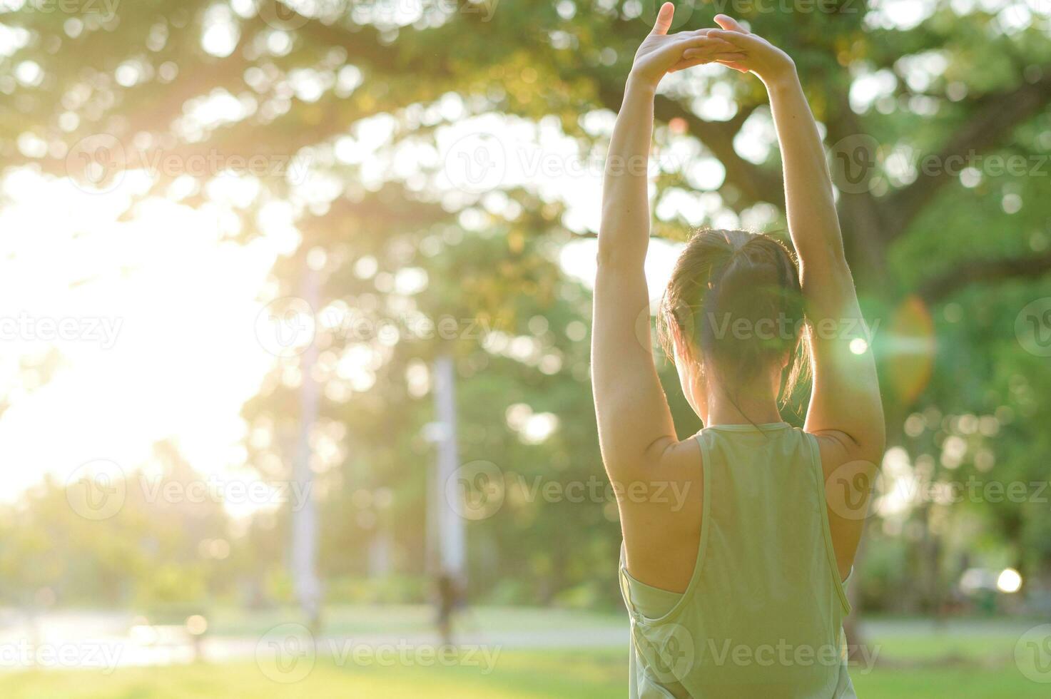 Female jogger. Fit young Asian woman with green sportswear stretching muscle in park before running and enjoying a healthy outdoor. Fitness runner girl in public park. Wellness being concept photo