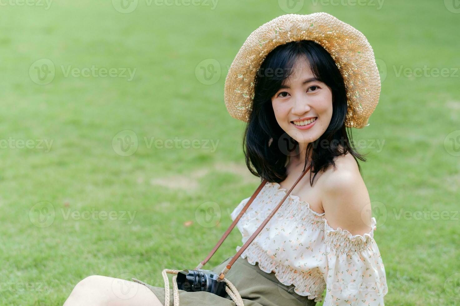 retrato de asiático joven mujer viajero con Costura sombrero y cesta y un cámara en verde público parque naturaleza antecedentes. viaje viaje estilo de vida, mundo viaje explorador o Asia verano turismo concepto. foto