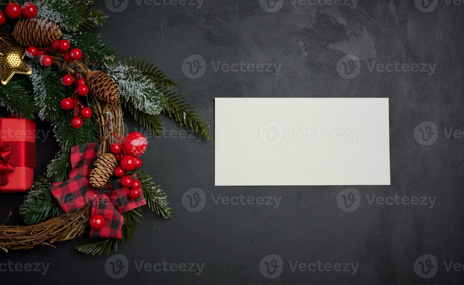White envelope and Christmas wreath on a black background, top view photo