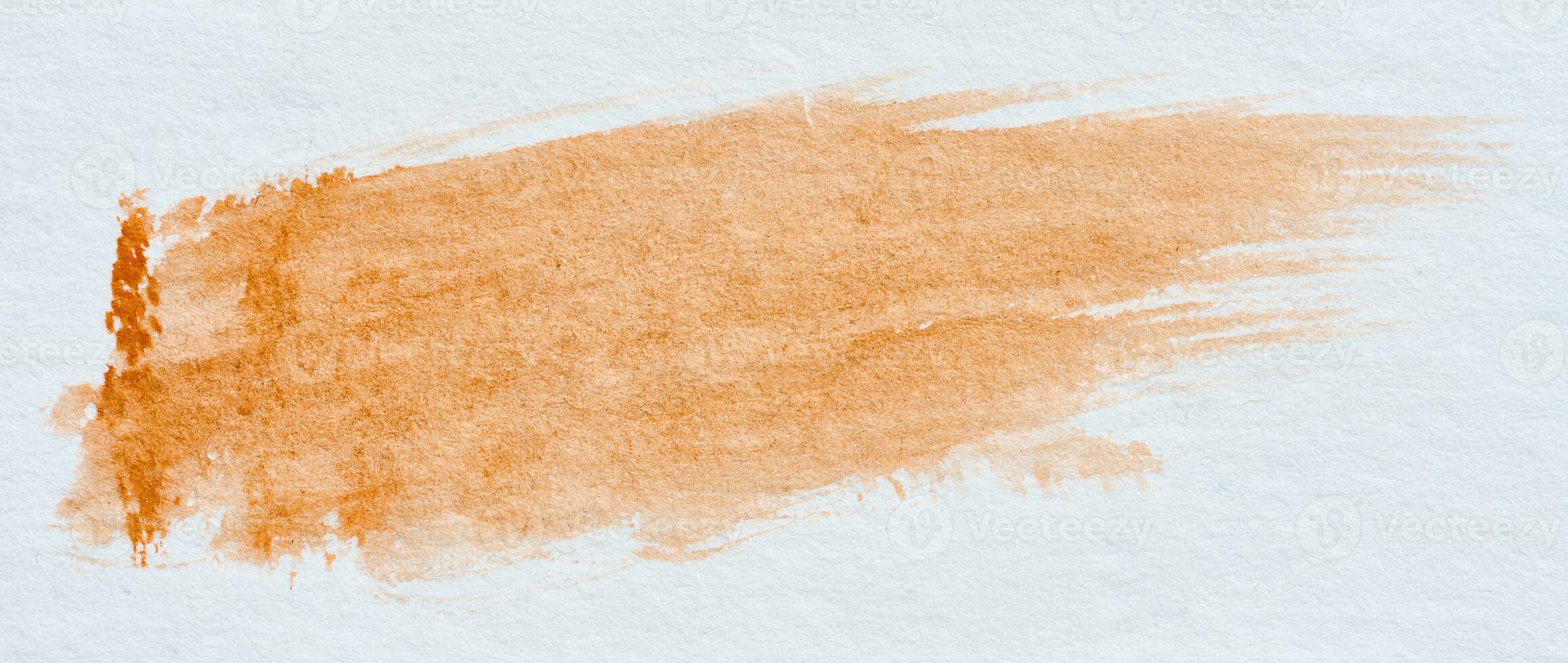 A stroke of orange watercolor paint on a white sheet of paper photo