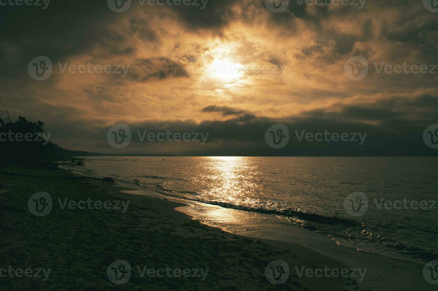 Sunset on the west beach on the Baltic Sea. Waves, beach, cloudy sky and sunshine photo