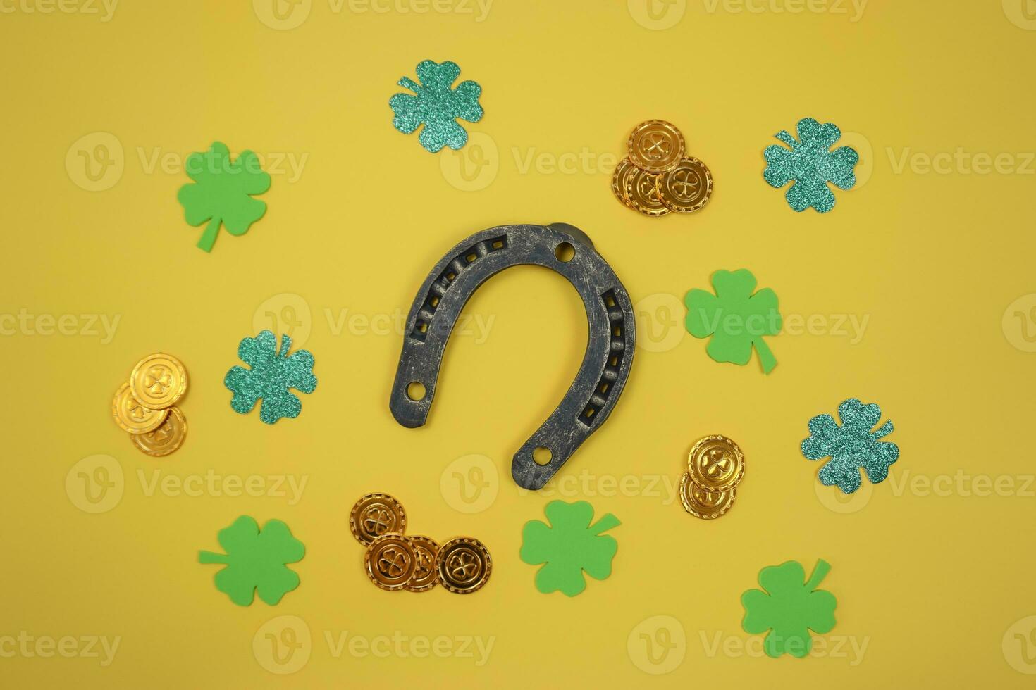 On a yellow background lies an ancient horseshoe , four leaf clover leaves and St. Patrick 's coins photo