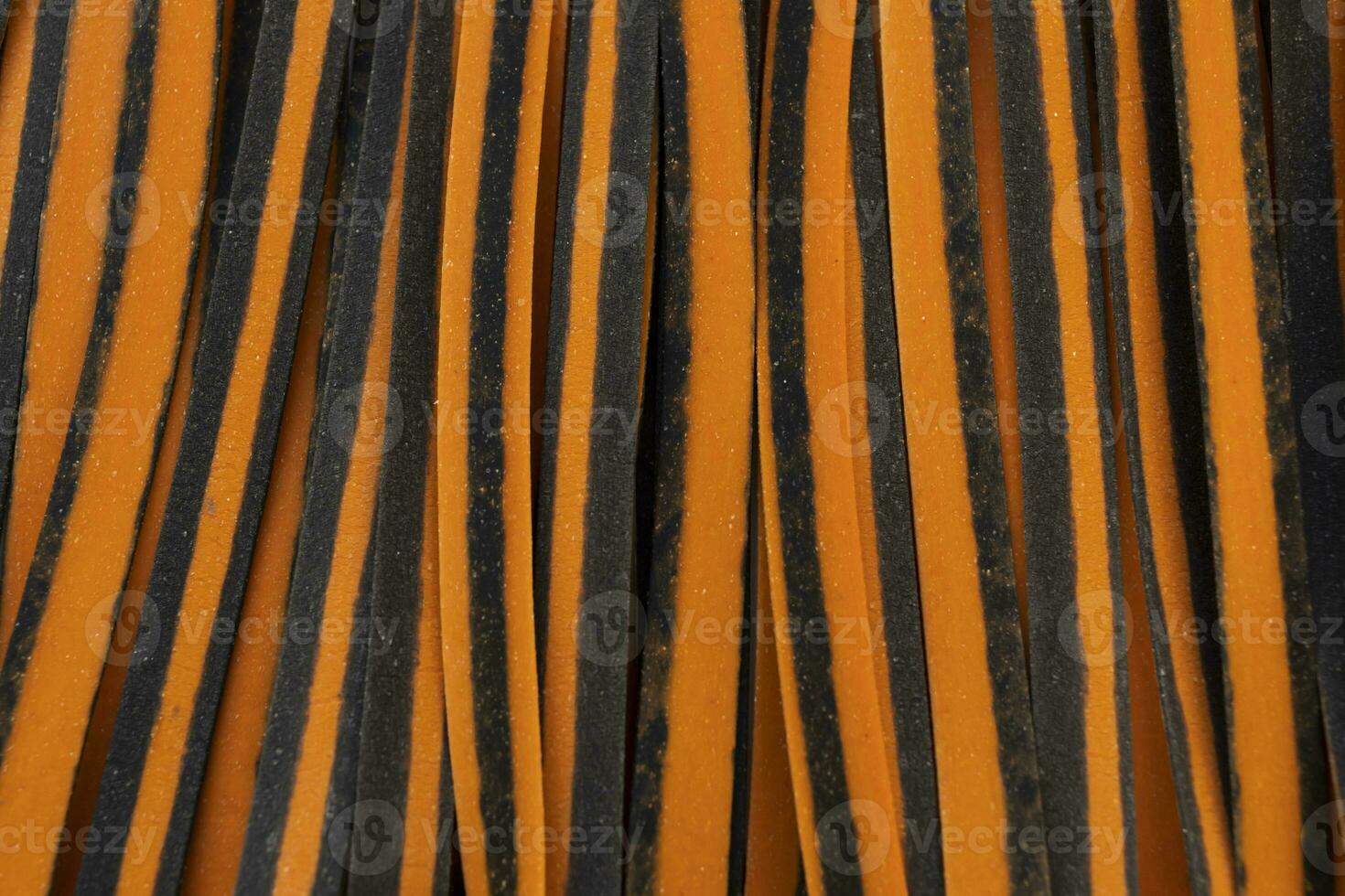 Closeup Black And Orange Pappardelle Italian Pasta, Fresh Wheat Product, Background And Texture. Top View. Egg Dry Ribbon Noodles, Long Rolled Macaroni or Uncooked Spaghetti. Horizontal Macro Flatly photo