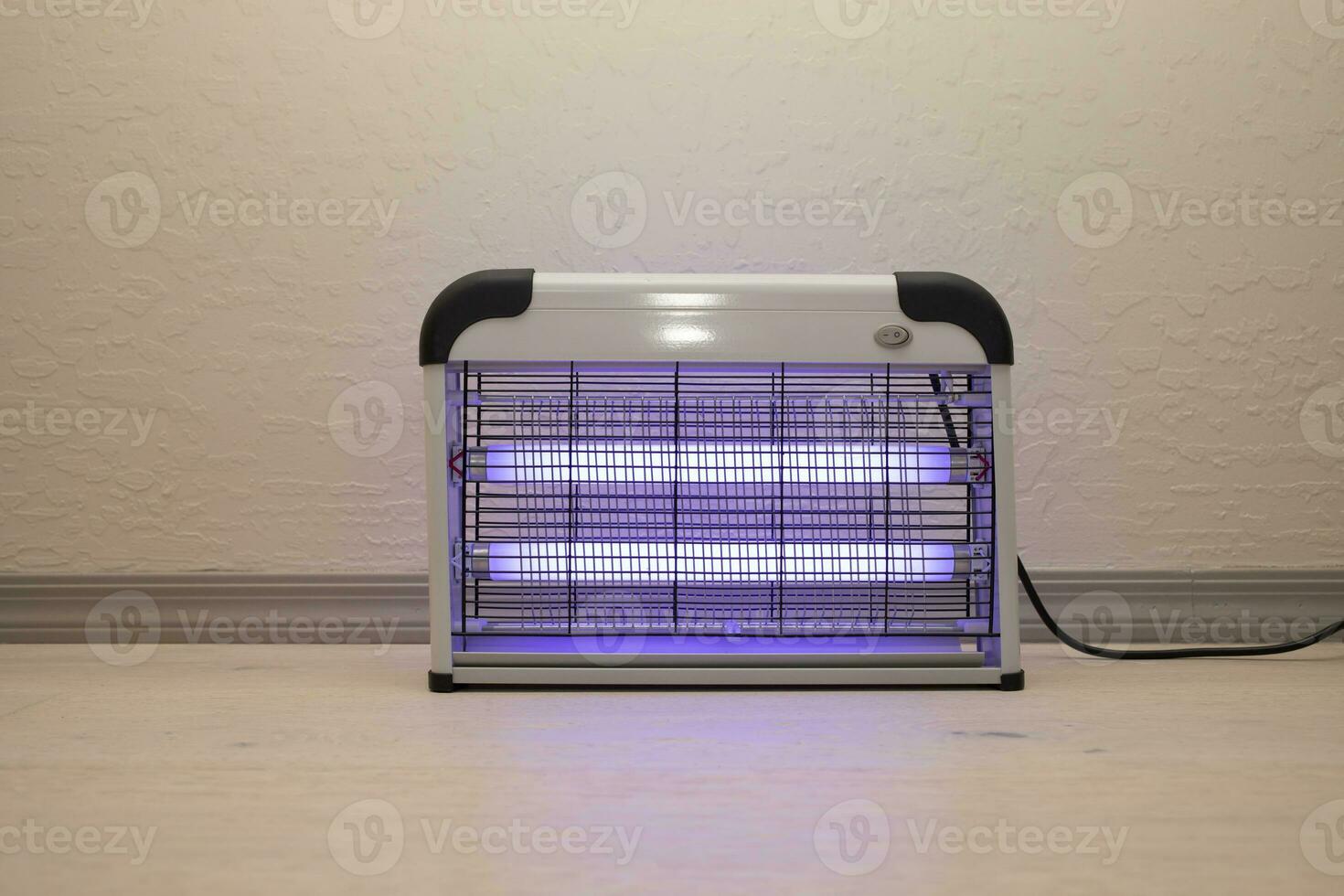 Electric Mosquito and Insect Zapper With Blue Purple Lights Turned on. Bug Killer Lamp on Wooden Floor in Room. Fly Trap for Outdoor and Indoor. Horizontal Plane photo