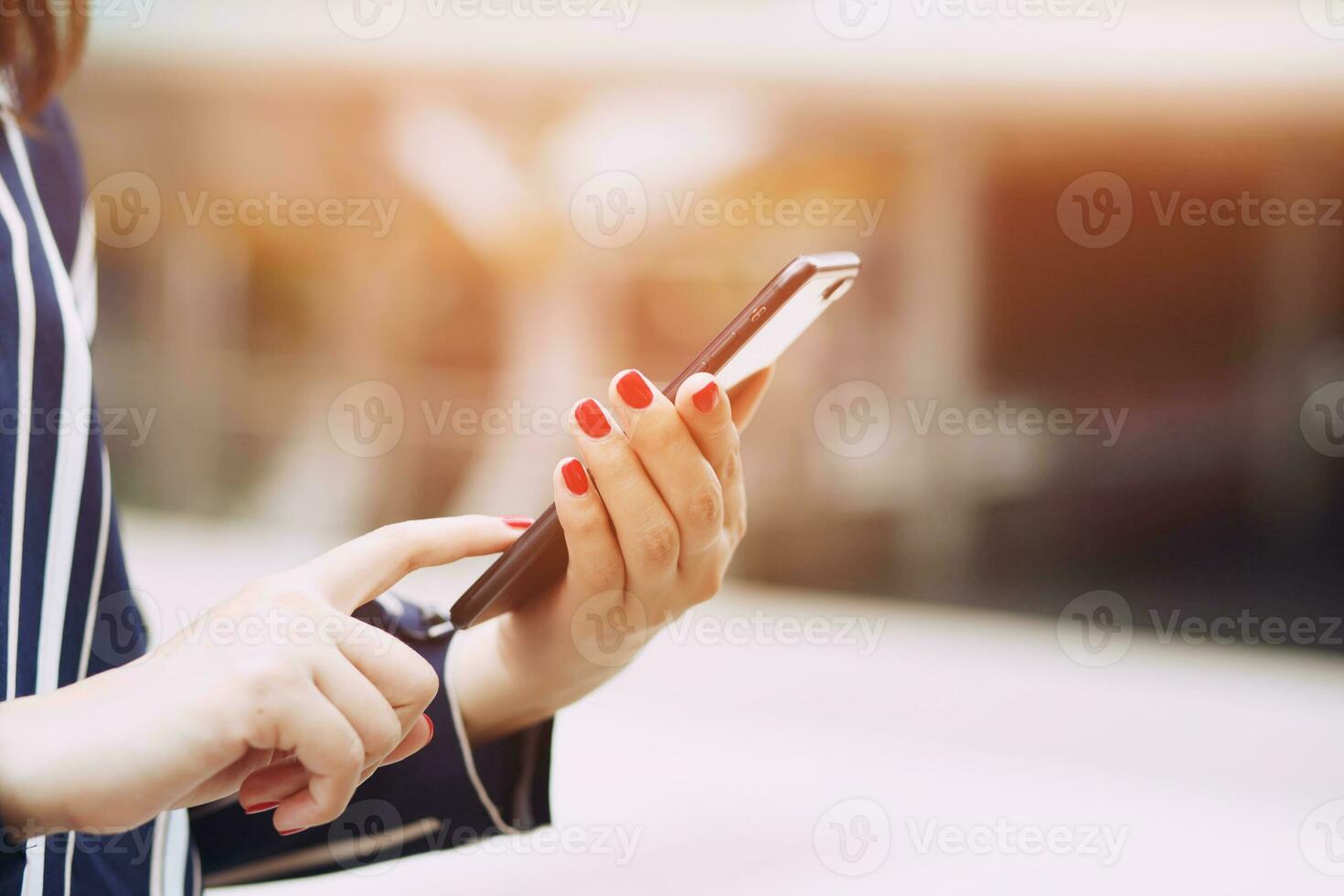 female hand holding pointing finger on screen mobile smartphone touching screen and using app. information content,  reading text message on cell telephone during in urban. photo