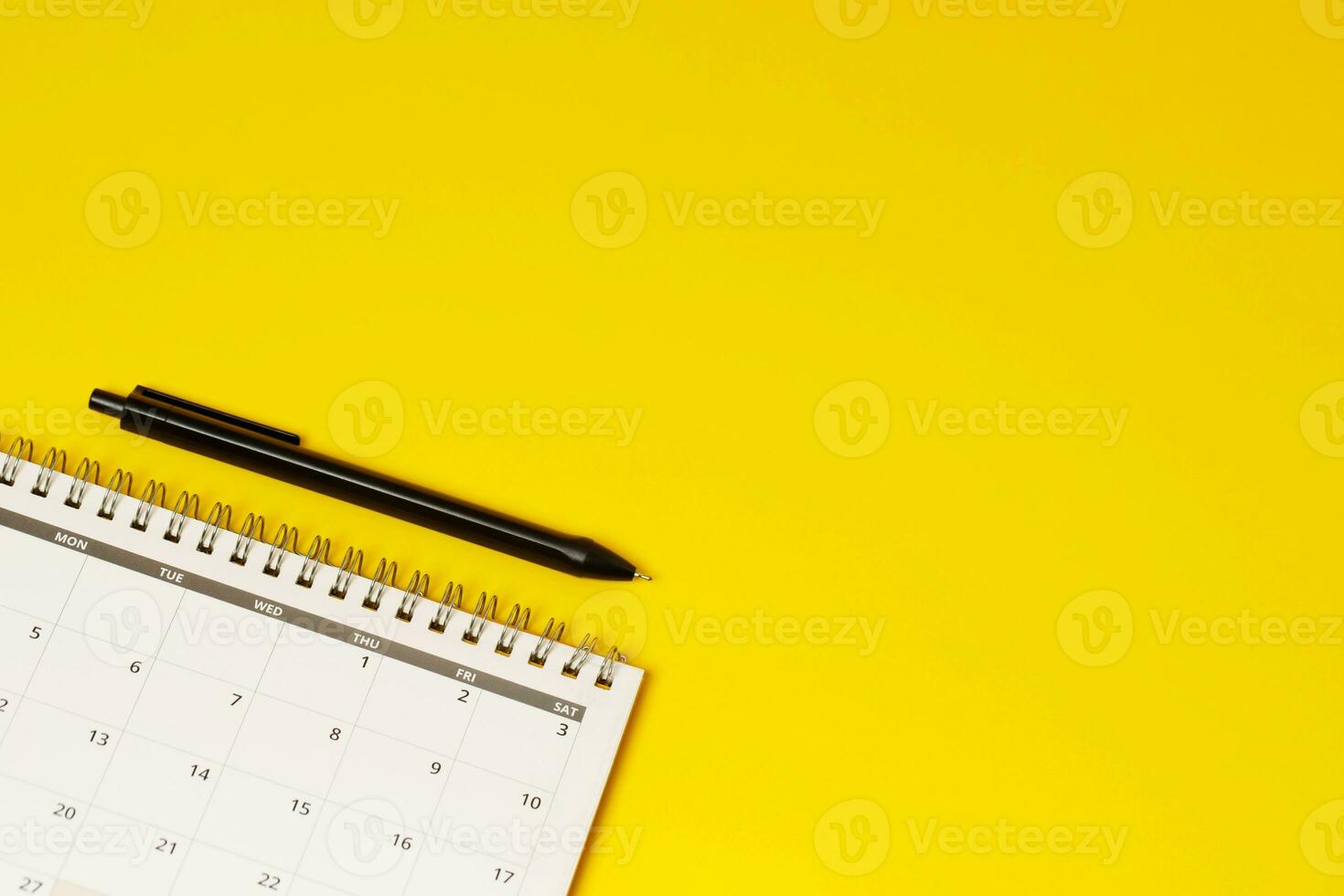 calendar month schedule to make appointment meeting or manage timetable each day lay and pen on yellow background for planning work and travel concept. photo