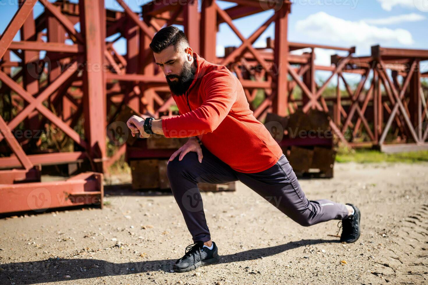 Adult man is exercising outdoor on sunny day. He is stretching his body. photo