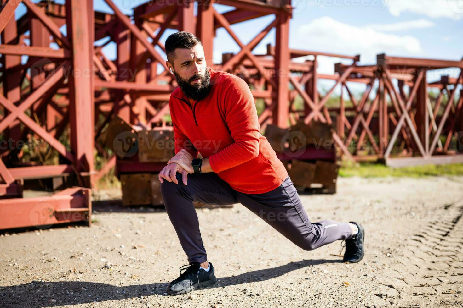 Adult man is exercising outdoor on sunny day. He is stretching his body. photo