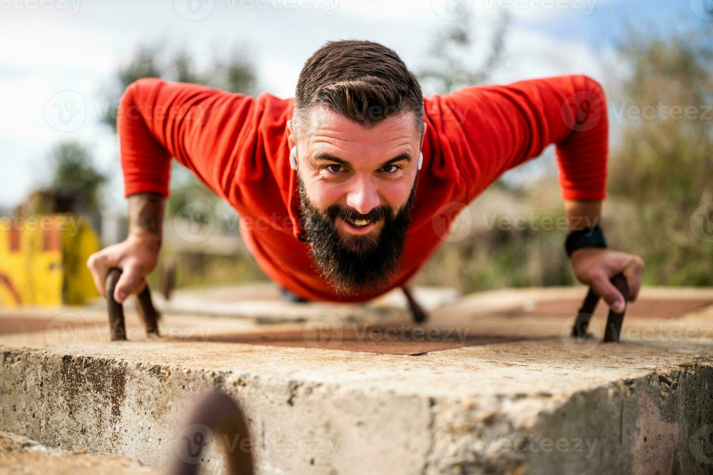 Young happy man is exercising outdoor. He is doing push-ups. photo