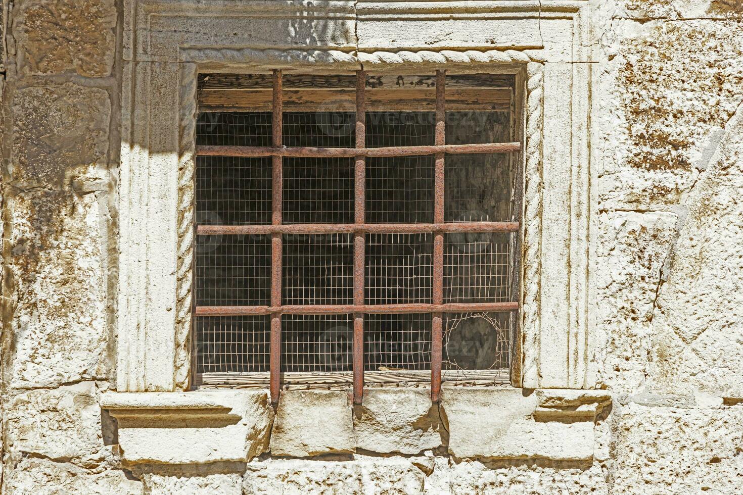 Picture of an old barred window with rusty bars in the sunlight photo