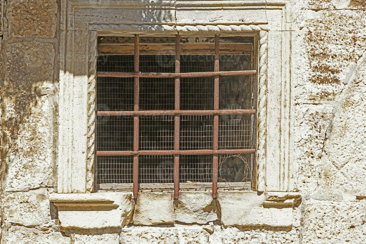 imagen de un antiguo prohibido ventana con oxidado barras en el luz de sol foto