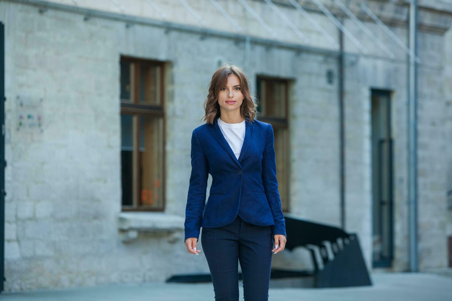 Portrait of a successful business woman in front of modern business building. Young manager poses outside. Woman employee of an office. photo