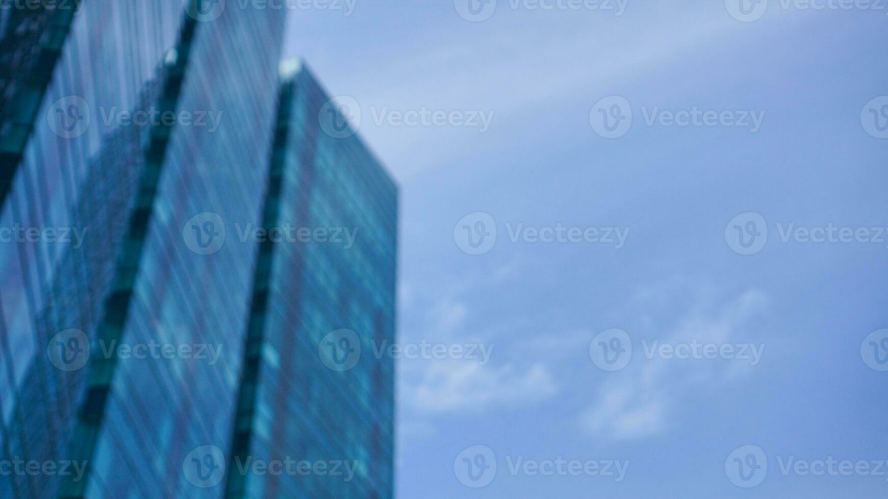 Defocused bottom view blue glasses building with sky and cloud background. Blurred Skyscraper, view of modern business building. defocused modern blue glasses building landscape. photo