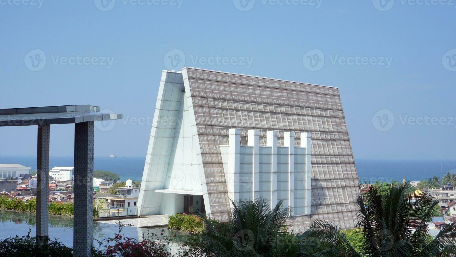 A triangular shaped architectural building with a background of blue sea and sky photo