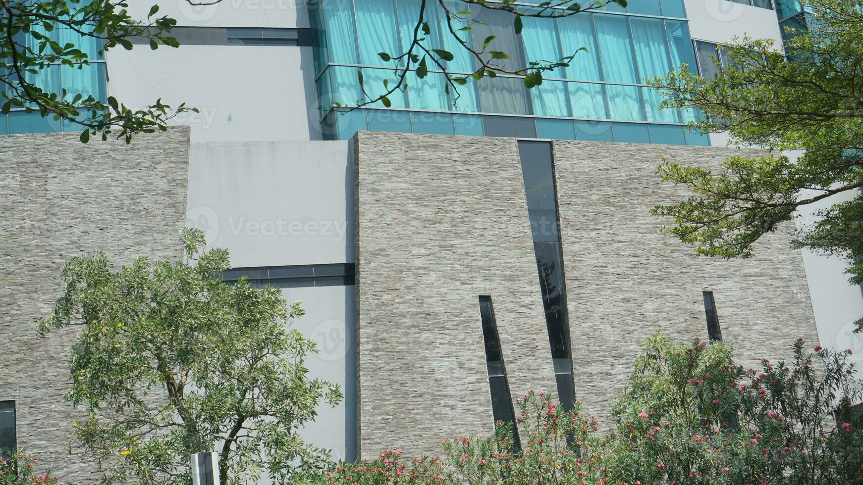 The exterior of the building is decorated with gray granite and blue glass with trees around it for mock up photo