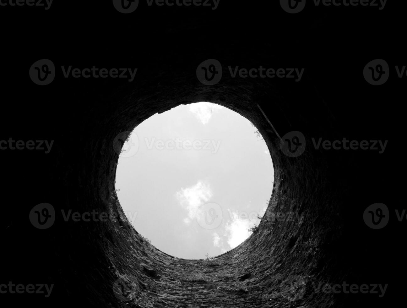 Stone well hole, old construction from inside, brick walls and blue sky background, fall down in the well concept photo