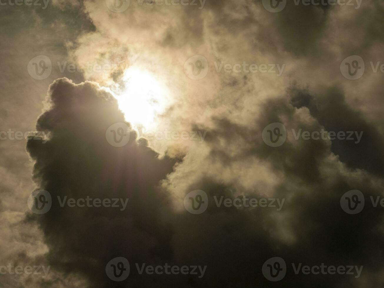 Fluffy clouds over sunset sky and sun rays. Fluffy cumulus cloud shape photo, gloomy cloudscape background, smoke in the sky photo