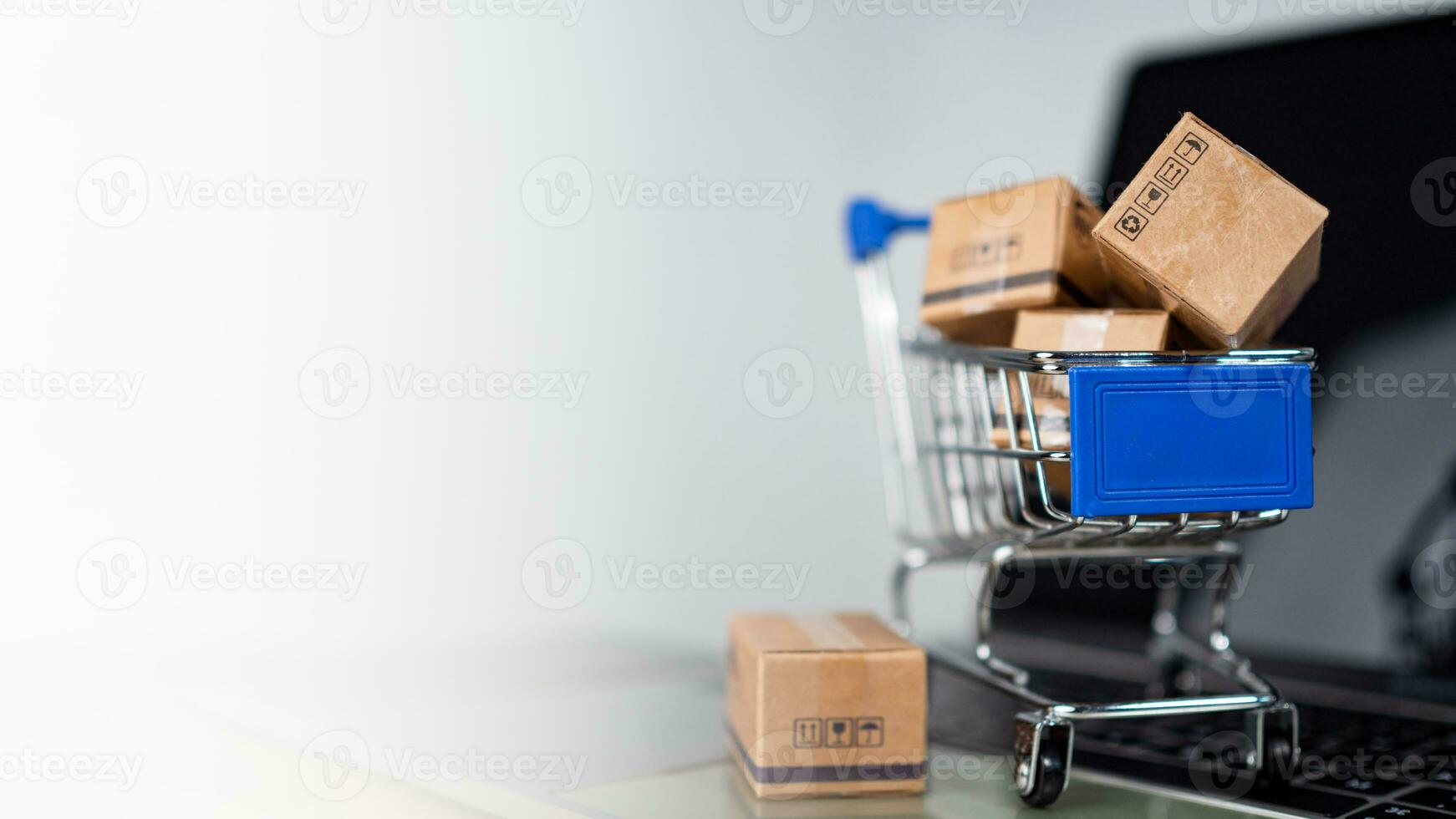 Shopping cart and product boxes on laptop computer on white background and copy space. online shopping marketplace platform website E-commerce technology and online payment concepts. photo