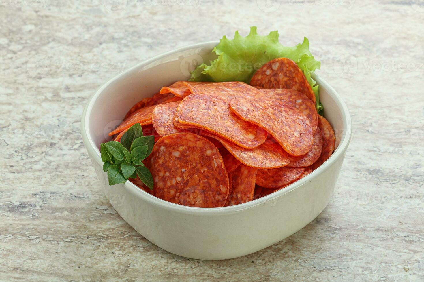 Sliced pepperoni sausage in the bowl photo